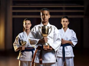 A trio of black belt martial arts students holding trophies
