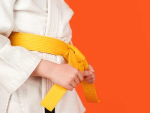a beginner martial arts student tightening their yellow colored belt