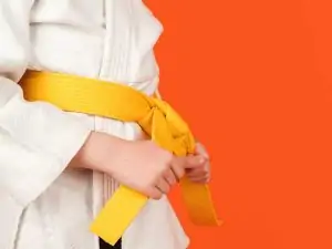 a beginner martial arts student tightening their yellow colored belt